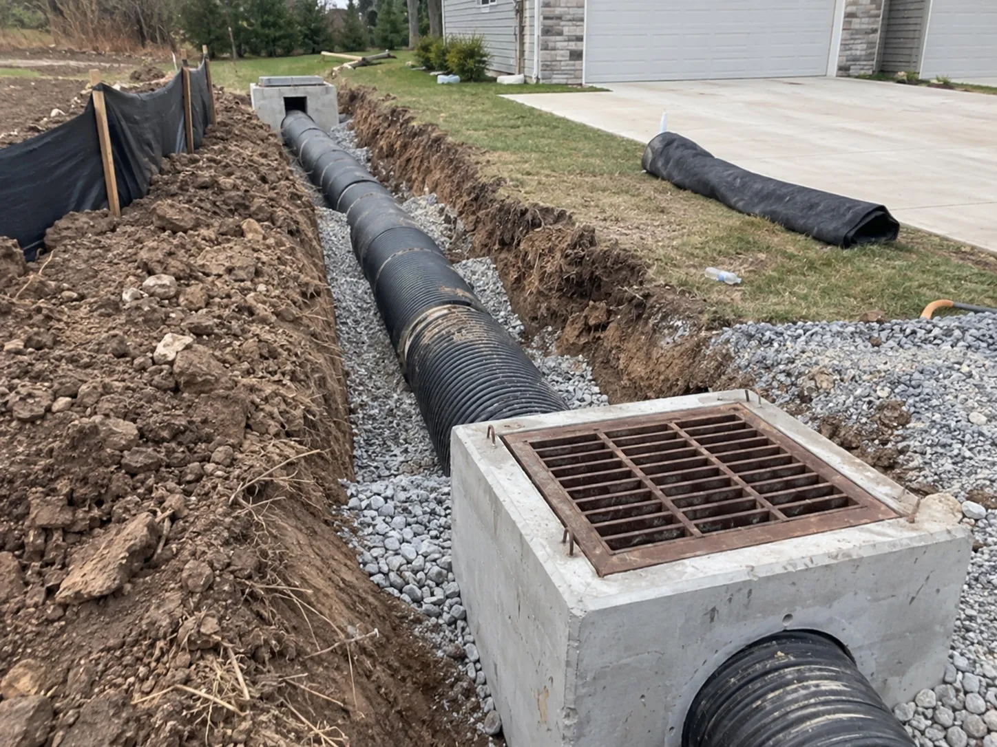 Stormwater pipe and grated sump installed in a gravel-bedded trench in Hamilton